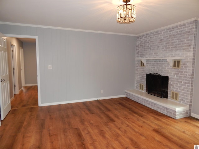 unfurnished living room featuring a chandelier, hardwood / wood-style flooring, brick wall, and a brick fireplace