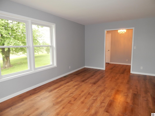 spare room with hardwood / wood-style flooring and a chandelier