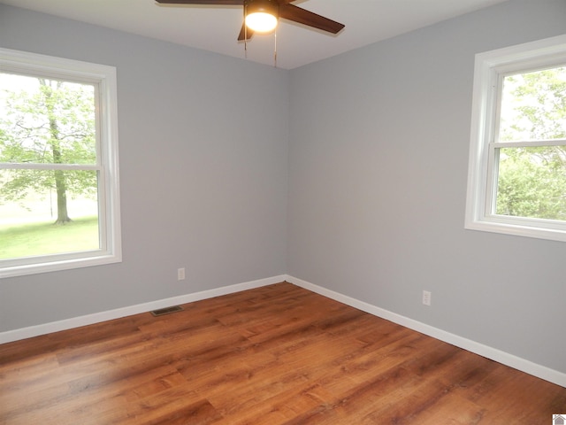 unfurnished room featuring plenty of natural light, ceiling fan, and hardwood / wood-style flooring