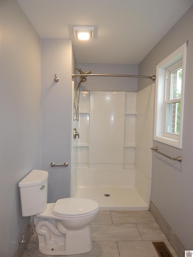 bathroom with tile flooring, toilet, and a shower