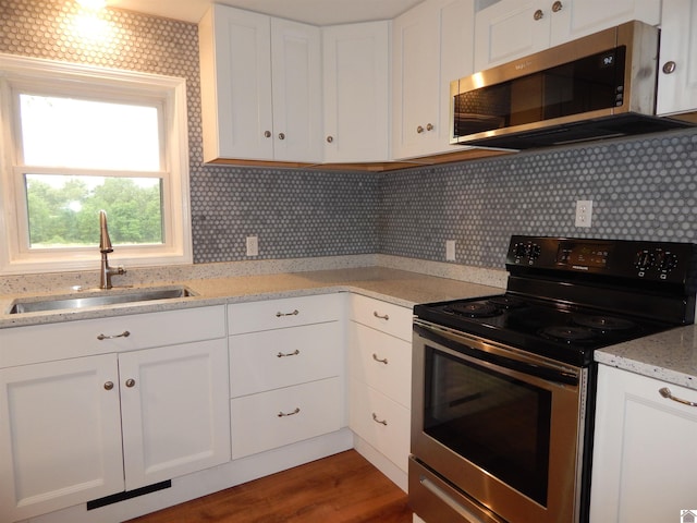 kitchen featuring sink, backsplash, white cabinetry, and appliances with stainless steel finishes