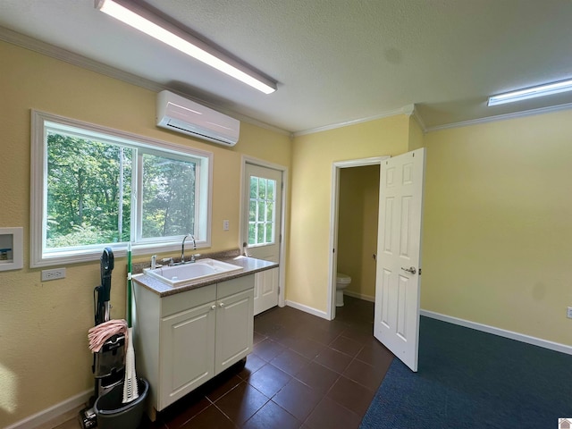 kitchen featuring plenty of natural light, a wall mounted air conditioner, dark tile flooring, sink, and white cabinetry