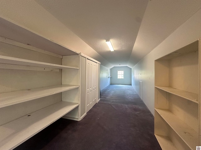 hallway featuring carpet flooring, a textured ceiling, and lofted ceiling