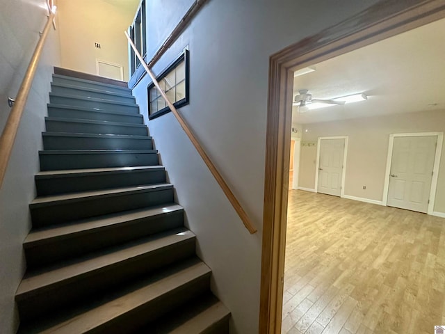 stairs with light wood-type flooring and ceiling fan