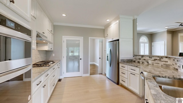 kitchen with stainless steel appliances, tasteful backsplash, white cabinets, and light wood-type flooring