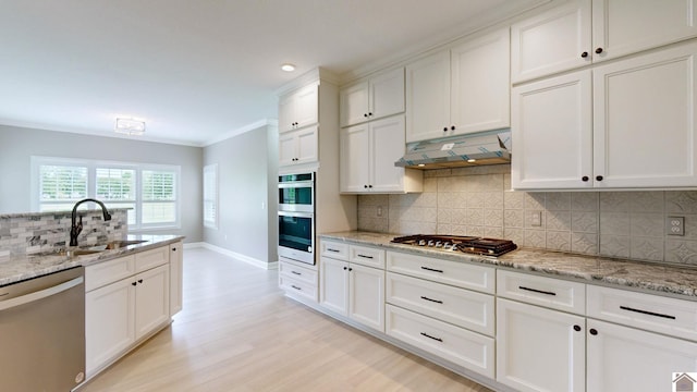 kitchen with light hardwood / wood-style floors, tasteful backsplash, white cabinetry, and appliances with stainless steel finishes