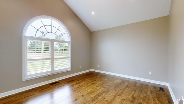 unfurnished room with high vaulted ceiling and wood-type flooring