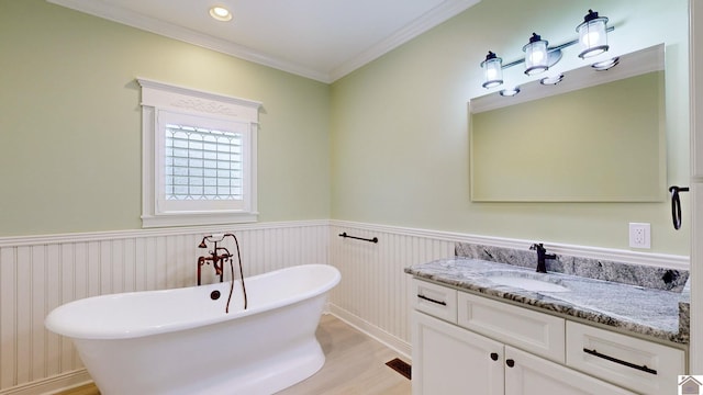 bathroom featuring a tub, hardwood / wood-style floors, vanity, and ornamental molding