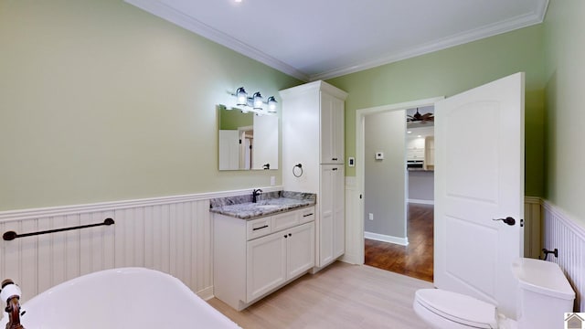 bathroom featuring ceiling fan, hardwood / wood-style floors, oversized vanity, a bath to relax in, and toilet