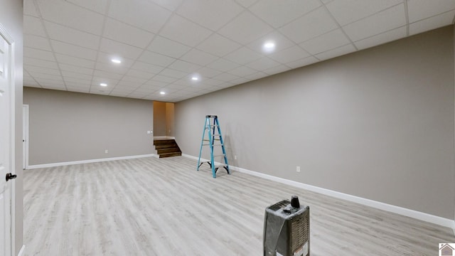 exercise area with light wood-type flooring and a paneled ceiling