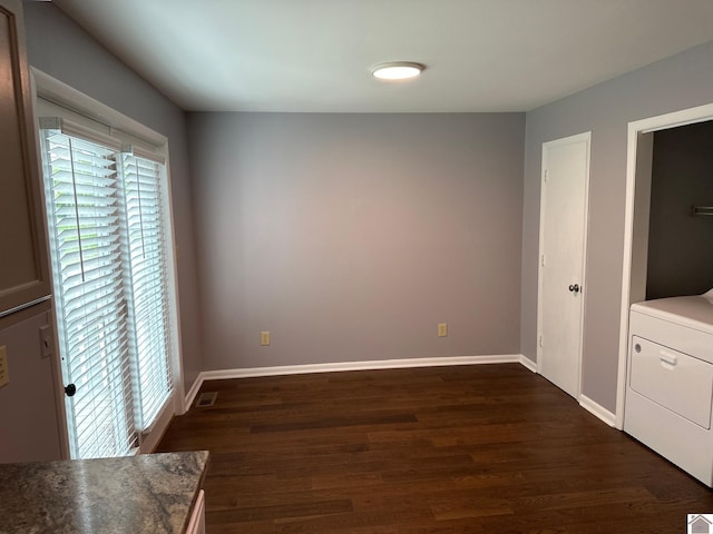 unfurnished bedroom featuring washer / dryer and dark wood-type flooring