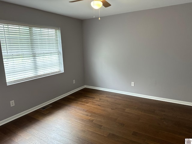 spare room featuring ceiling fan, a healthy amount of sunlight, and dark wood-type flooring