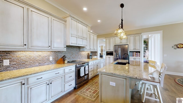 kitchen with light stone countertops, decorative light fixtures, stainless steel appliances, and a kitchen island with sink