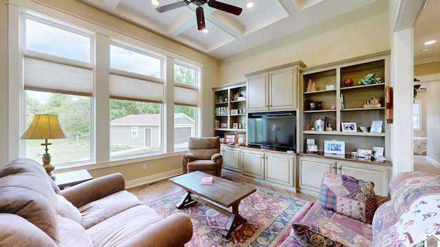 living room featuring beam ceiling, light hardwood / wood-style flooring, ceiling fan, and coffered ceiling