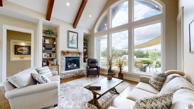 living room featuring beam ceiling, built in shelves, high vaulted ceiling, a fireplace, and light wood-type flooring