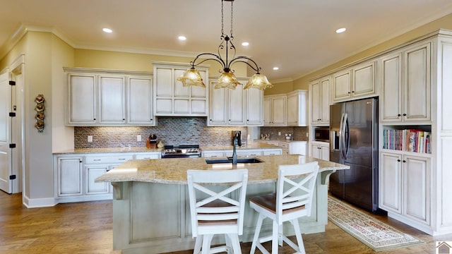 kitchen featuring appliances with stainless steel finishes, a kitchen breakfast bar, sink, decorative light fixtures, and an island with sink