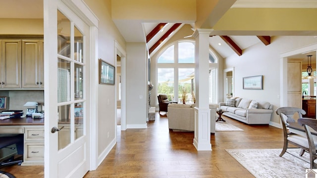 foyer entrance featuring vaulted ceiling with beams, built in desk, ornate columns, and dark wood-type flooring