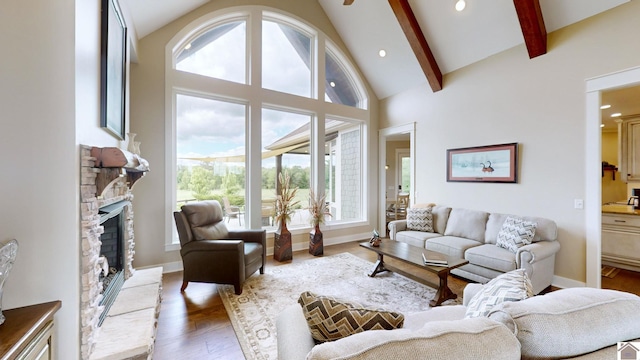 living room with beam ceiling, a stone fireplace, wood-type flooring, and high vaulted ceiling