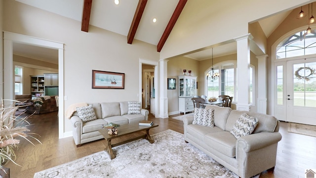 living room featuring wood-type flooring, decorative columns, a wealth of natural light, and a notable chandelier