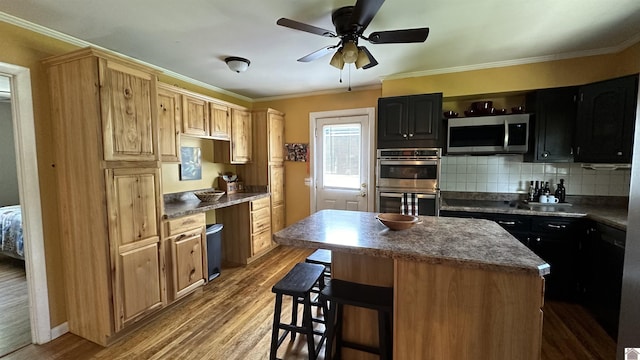 kitchen with crown molding, a kitchen island, hardwood / wood-style floors, and appliances with stainless steel finishes