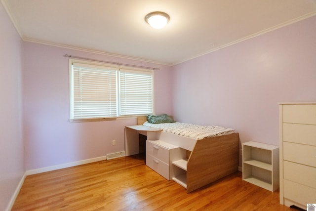 bedroom featuring crown molding and light hardwood / wood-style flooring