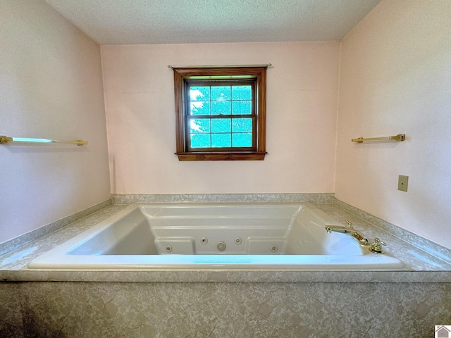 bathroom with tiled tub and a textured ceiling