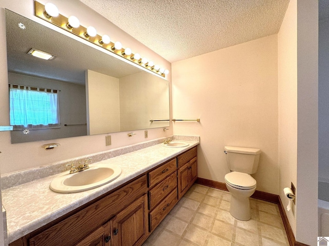 bathroom with vanity, toilet, and a textured ceiling