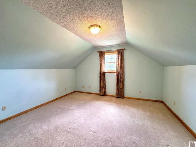 additional living space featuring light carpet, vaulted ceiling, and a textured ceiling