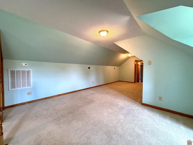 bonus room featuring vaulted ceiling, light carpet, and a textured ceiling