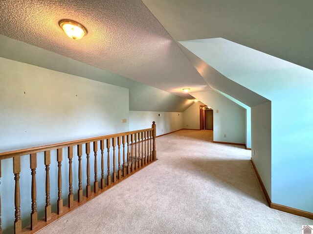 bonus room featuring vaulted ceiling, light carpet, and a textured ceiling