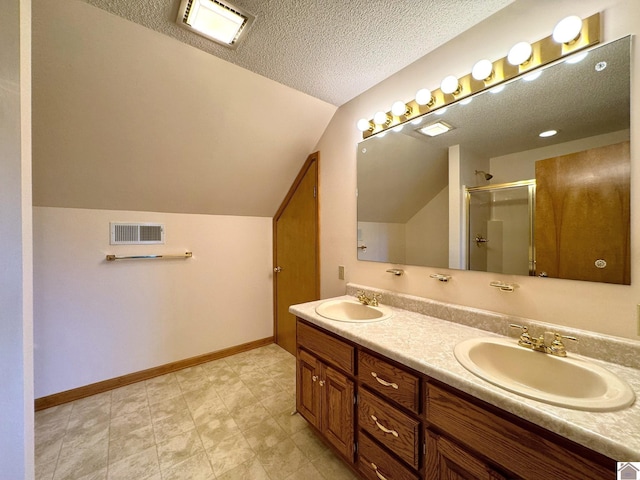 bathroom with lofted ceiling, a shower with door, a textured ceiling, and vanity