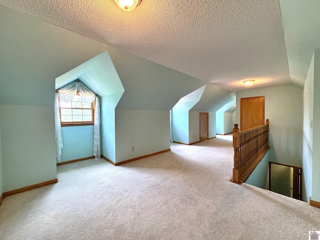 bonus room with lofted ceiling, light carpet, and a textured ceiling