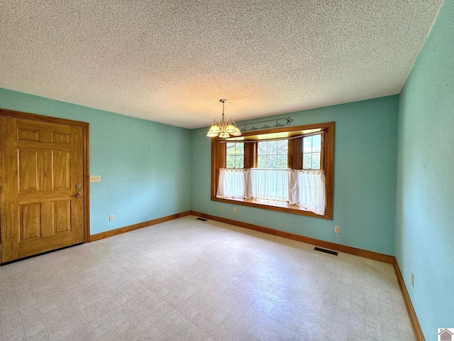 empty room featuring a notable chandelier and a textured ceiling