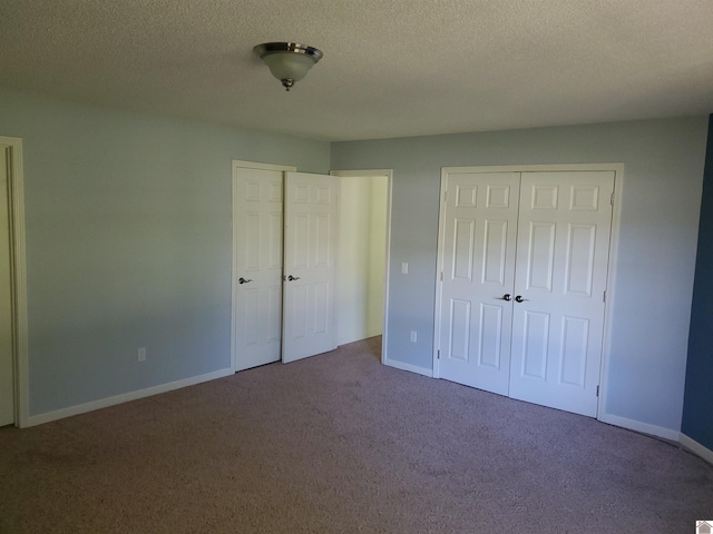 unfurnished bedroom featuring multiple closets, carpet, and a textured ceiling