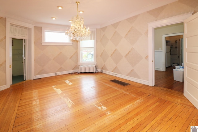 unfurnished room with radiator, crown molding, light hardwood / wood-style flooring, and an inviting chandelier