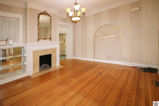 unfurnished living room with hardwood / wood-style flooring, ornamental molding, a fireplace, and a chandelier