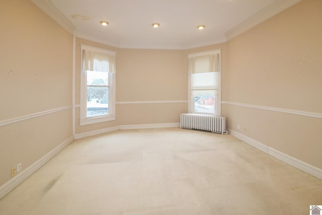 carpeted spare room with crown molding and radiator heating unit