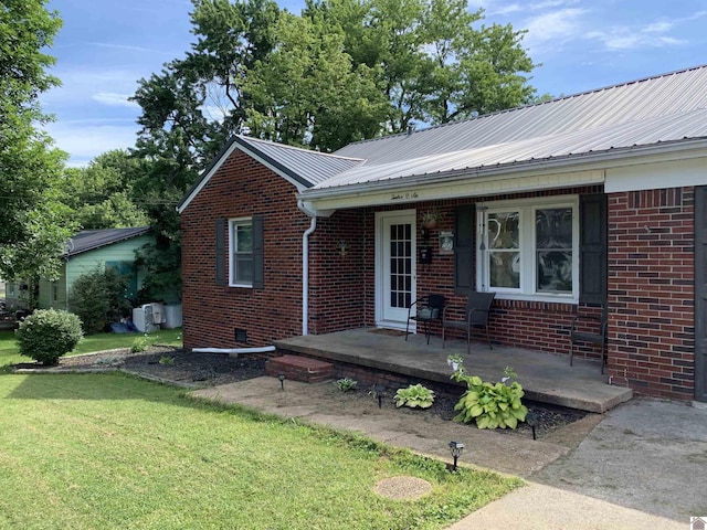 view of front of home featuring covered porch, brick siding, metal roof, and a front lawn