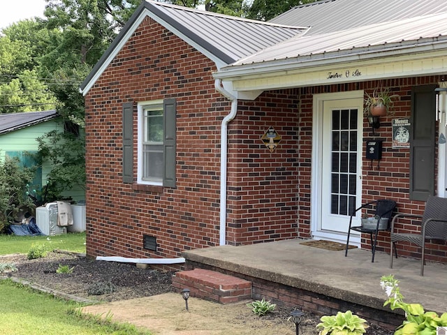 property entrance featuring metal roof, brick siding, and crawl space