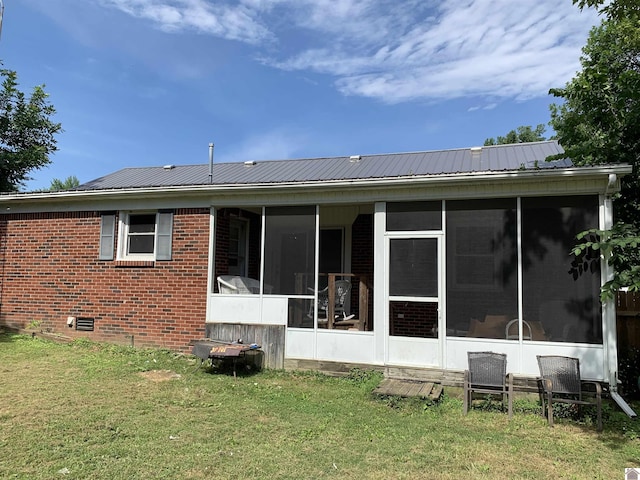 back of house featuring a sunroom, metal roof, crawl space, a yard, and brick siding