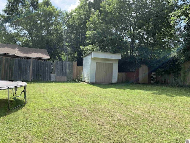 view of yard featuring a trampoline, an outbuilding, a fenced backyard, and a storage shed