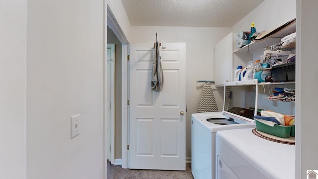 washroom with washing machine and clothes dryer, cabinets, and a textured ceiling