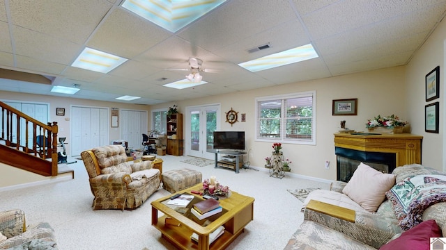 carpeted living room with ceiling fan and a drop ceiling