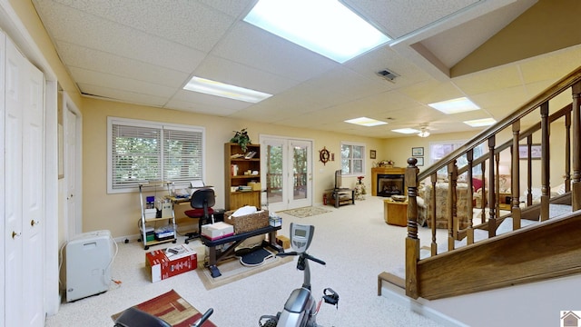 exercise area featuring a paneled ceiling, ceiling fan, carpet, and french doors