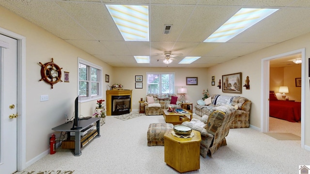 living room with ceiling fan, a drop ceiling, and carpet floors