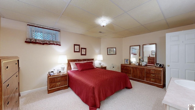 bedroom with light carpet, a paneled ceiling, and sink