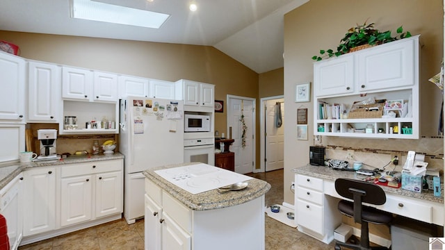 kitchen featuring white cabinets, a center island, white appliances, and lofted ceiling with skylight