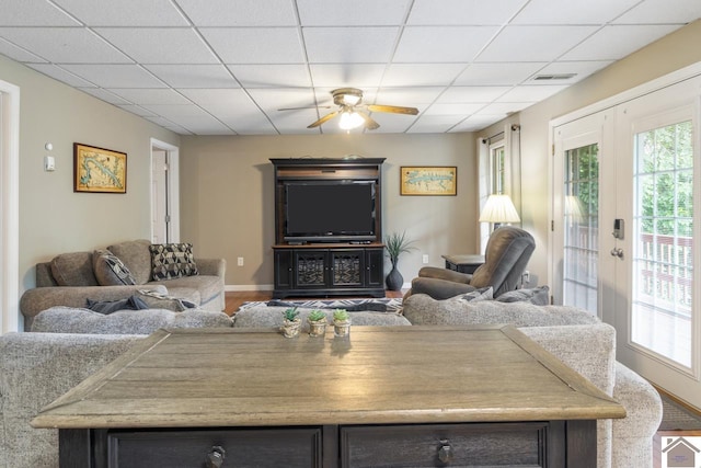 living room with a paneled ceiling, ceiling fan, hardwood / wood-style floors, and french doors