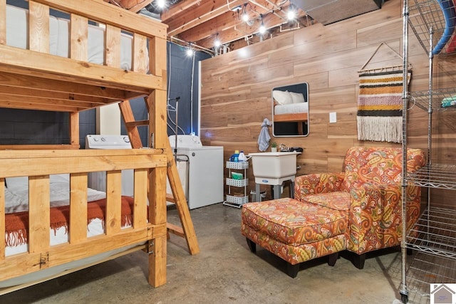 interior space featuring independent washer and dryer, sink, and wood walls