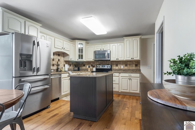 kitchen featuring appliances with stainless steel finishes, a center island, tasteful backsplash, and light hardwood / wood-style flooring